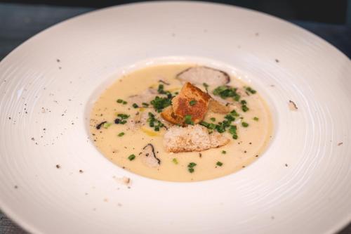 a white plate with a bowl of soup with food at Marienhöh - Hideaway & Spa in Langweiler