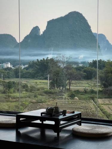 a room with a table in front of a large window at Yangshuo Mountain Vista Courtyard in Yangshuo