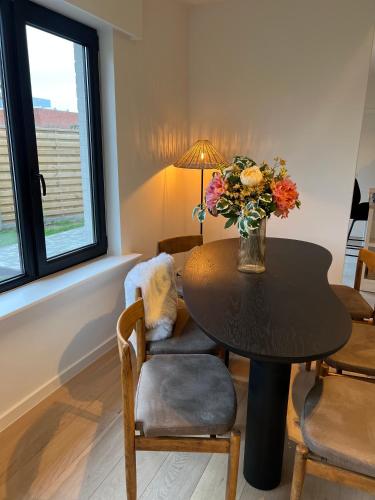 a dining room with a table with a vase of flowers at Maison Olive in Torhout