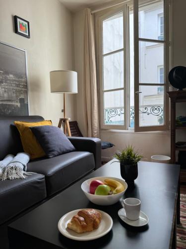 un salon avec un canapé et une table avec un bol de fruits dans l'établissement Cozy 1BR in the Heart Of Paris, à Paris