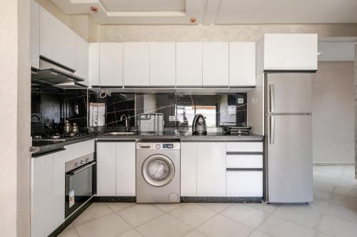 a kitchen with white cabinets and a washing machine at Appartamento con piscina privata in Pont Blondin