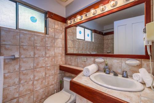 a bathroom with a sink and a toilet and a mirror at Ocean and Mountain View Villa in Playa Hermosa