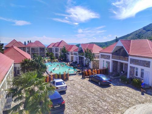 a resort with a swimming pool with cars and houses at Garden F Sheki in Sheki