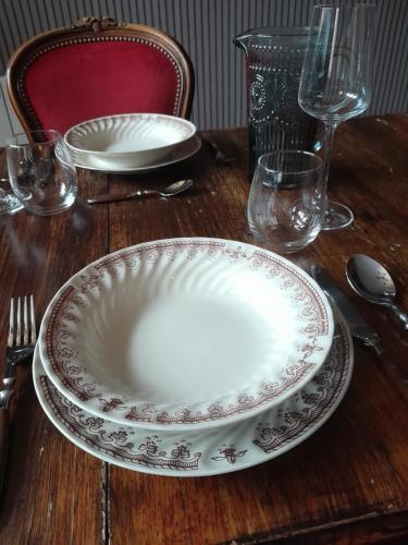 a wooden table with two plates and glasses on it at Escapade en Alsace - gîte de charme pour deux à Bergheim in Bergheim