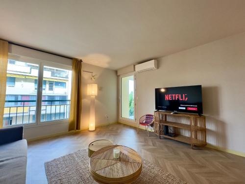 un salon avec une télévision et une table dans l'établissement Le Montébello By SCLS Locations, à Cannes