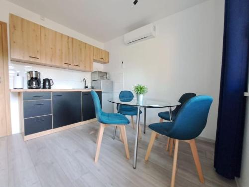 a kitchen with a table and blue chairs at Domki Kajuta 3 in Żarnowska