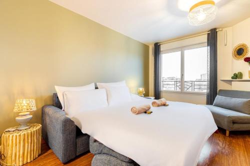 Un dormitorio con una gran cama blanca y un sofá. en GuestReady - Charmant Apt pour 2 près de Paris, en Saint-Ouen
