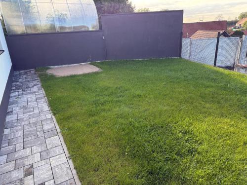 a yard with green grass and a fence at Byt apartman 72m2 private garden PARKING FREE in Prague