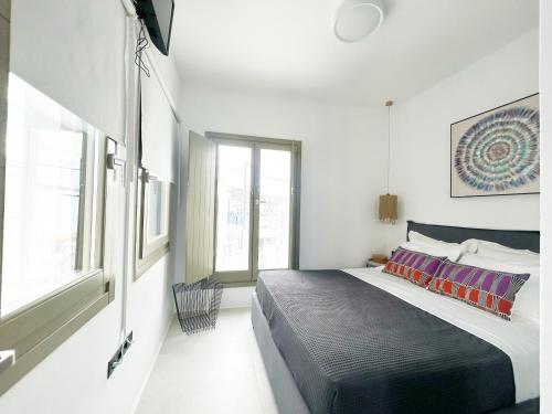 Un dormitorio con una cama grande y una ventana. en Joelia Suites in Naousa Paros with private jacuzzi!, en Naousa