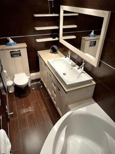 une salle de bain avec un lavabo, des toilettes et un miroir dans l'établissement Apt 8p, ski-in, ski-out, parking, à Méribel