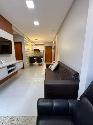 a living room with a leather couch and a television at Apartamento Concierge Sensacional in Marabá