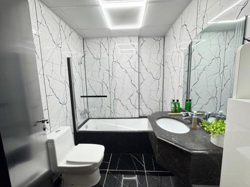 a bathroom with a toilet and a sink and a tub at Stay in the heart of Sport City in LUX 1BDR with sky view 11 in Dubai