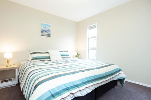 a white bedroom with a bed and a window at Alpine Nook in Methven