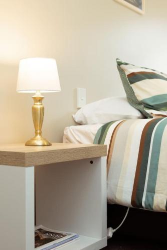 a bedroom with a bed with a lamp on a night stand at Alpine Nook in Methven