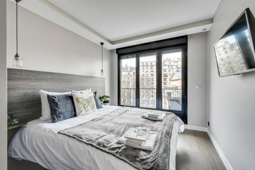 une chambre avec un grand lit et une grande fenêtre dans l'établissement Bluestay 54 - Superbe appartement à Paris, à Paris
