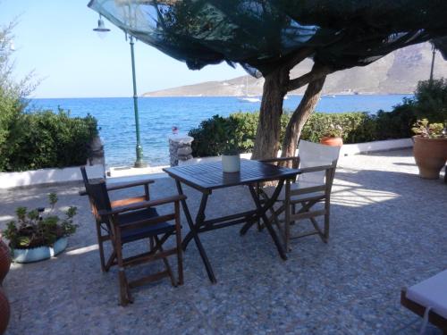 a table with two chairs and a tree and the ocean at ANEMOESSA APTS in Livadia