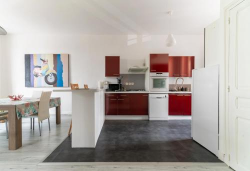 ヴィシーにあるLe Louis B - Appartement calme et lumineux proche Thermesの白いキッチン(赤いキャビネット、テーブル付)
