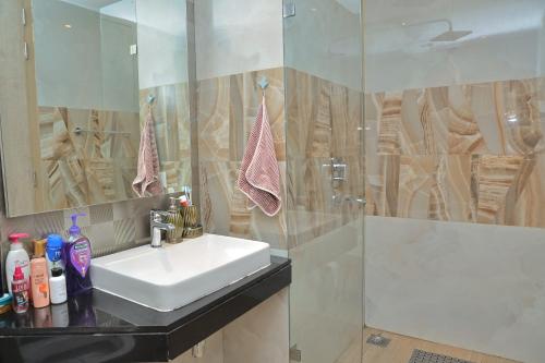 um banheiro com uma pia branca e um chuveiro em High Rise Den 1 em Gurgaon