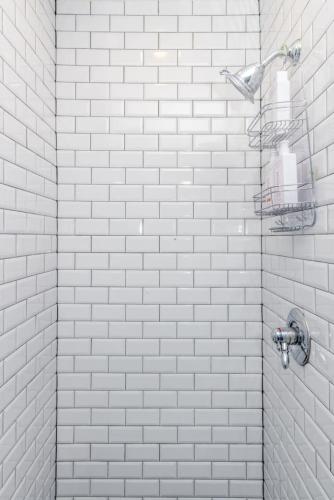 a white tiled shower in a bathroom with white tiles at Luxury Brownstone - Walk to ALL - Washington Park in Cincinnati