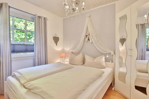 a white bedroom with a white canopy bed with white pillows at Ferienhaus Ostseeferien bei Bella Appartement 1 in Schürsdorf