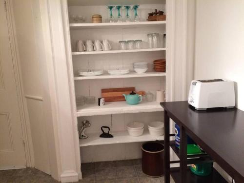 a kitchen pantry with white shelves filled with dishes at Charming Farmhouse in the City, Near Wine Country in Belleville