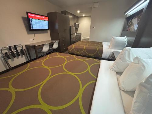 a hotel room with two beds and a flat screen tv at Super 8 by Wyndham Macleod Trail Calgary in Calgary
