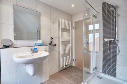 une salle de bain blanche avec lavabo et douche dans l'établissement "Klein-Wiebke" in der Villa Wilhelmine, à Borkum