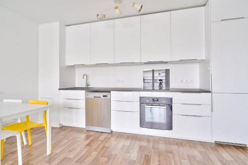 une cuisine avec des placards blancs, une table et des chaises jaunes dans l'établissement Chill & Work 3 près de La Défense, à Bezons