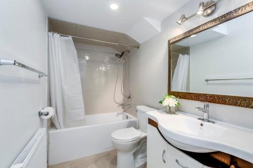 a bathroom with a sink and a toilet and a mirror at Midtown 2 Bedroom Apartment in Toronto