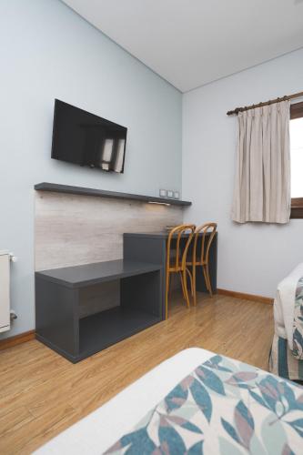 a bedroom with a desk and a tv on a wall at Hotel Bahia Nueva in Puerto Madryn