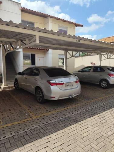 two cars parked in a parking lot in front of a house at Divino Apartamento Sete lagoas in Sete Lagoas