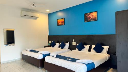 two beds in a room with a blue wall at Golden Pearl Resort By Gemstone Hospitality in Alibag