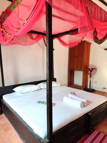 a bed in a room with a red canopy at Rafiki Backpackers-hostel in Nungwi