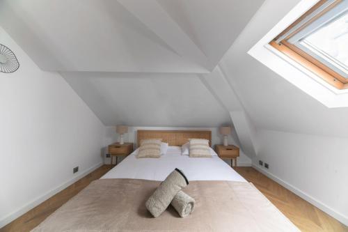 a white attic bedroom with a bed and a window at Résidence Serbie - Appartements design et climatisés en centre ville in Vichy