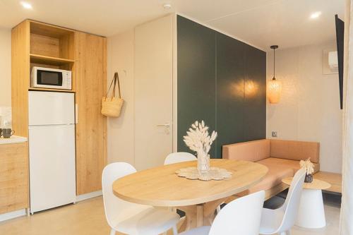 a dining room with a wooden table and white chairs at Camping Sènia Caballo de Mar in Pineda de Mar