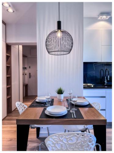 a dining room table with chairs and a pendant light at Balticus Playa Margarita in Międzyzdroje