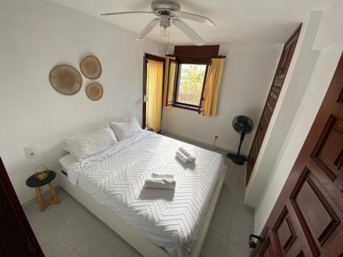 a bedroom with a white bed with a ceiling fan at Beach Appartement Denia in Denia
