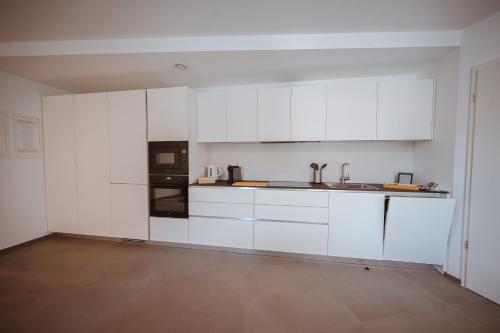a kitchen with white cabinets and a black appliance at Wake Up Lux City in Kirchberg