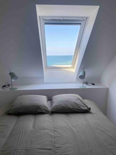 - une chambre avec un lit et une fenêtre au-dessus dans l'établissement Superbe appartement vue mer, à Perros-Guirec