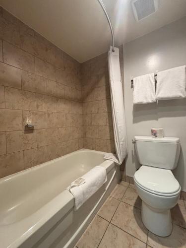 a bathroom with a toilet and a tub and a sink at Super 8 by Wyndham Macleod Trail Calgary in Calgary