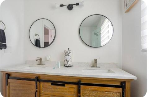a bathroom with two sinks and two mirrors on the wall at The Heart Of LA House in Los Angeles