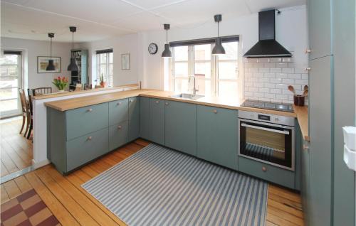 a kitchen with blue cabinets and a stove at Cozy Home In Samsø With Wifi in Kolby Kås