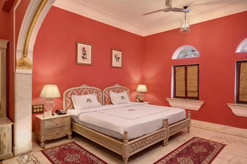 a bedroom with a bed in a red wall at Shahpura Haveli in Shāhpura