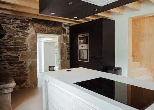 cocina con encimera blanca y electrodomésticos negros en Casa de Covés, en Puentedeume
