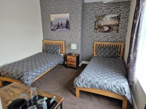 a room with two beds and a table with a table at Brookfield Hotel in Leeds