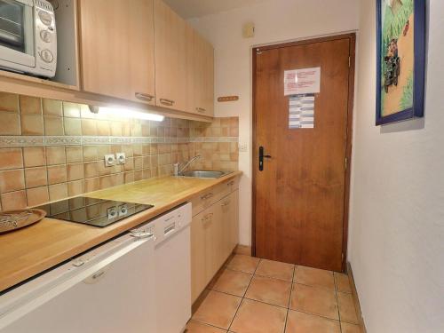 - une cuisine avec un évier et une porte en bois dans l'établissement Studio Skis aux Pieds, Plein Sud, Centre de Mottaret, 3/4 Pers., WiFi, Non-Fumeur - FR-1-182-6, à Méribel