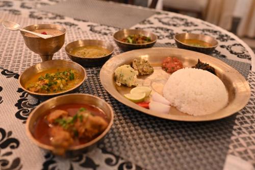 a table with a plate of food and bowls of food at Thengal Manor in Jorhāt