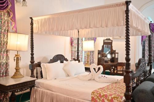 a bedroom with a canopy bed with two swans on it at Thengal Manor in Jorhāt