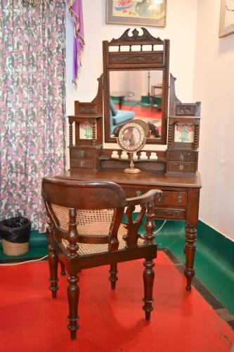 an antique dressing table with a mirror and a chair at Thengal Manor in Jorhāt