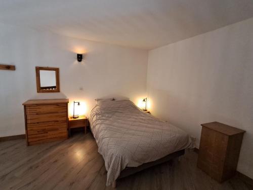 a bedroom with a bed and a mirror and two lamps at Appartement tout confort in Brides-les-Bains